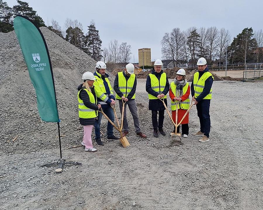 Sex personer med hjälm och reflexväst tar första spadtaget för nya Smedgärdsskolan med spadar i handen. Det är 4 politiker, kommunens utbildningschef och VD:n från Winge Byggnads AB som syns på bild. 