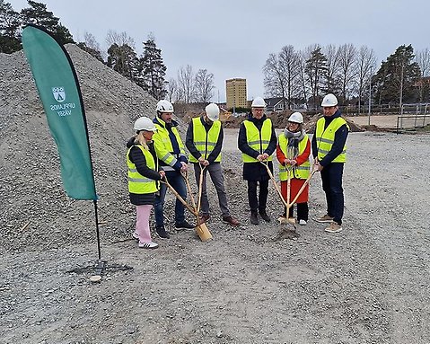 Sex personer med hjälm och reflexväst tar första spadtaget för nya Smedgärdsskolan med spadar i handen. Det är 4 politiker, kommunens utbildningschef och VD:n från Winge Byggnads AB som syns på bild. 