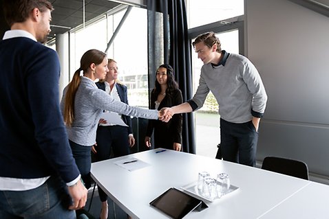 En kvinna och en man skakar hand i ett konferensrum.