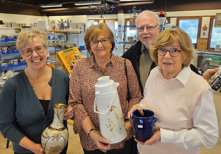 Tre kvinnor och en man håller upp saker som man kan köpa på Skopans second hand-butik.