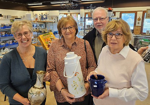 Tre kvinnor och en man håller upp saker som man kan köpa på Skopans second hand-butik.